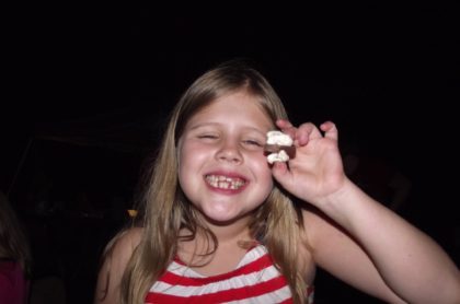 UUMAN members' child eating a s'more at camping trip.